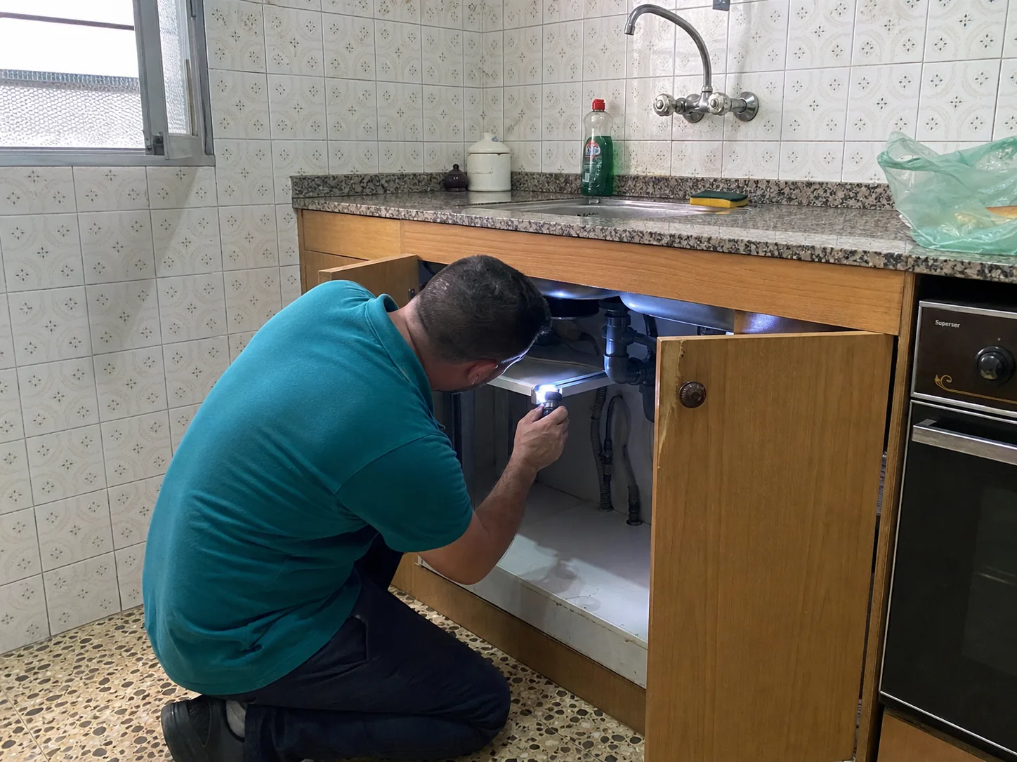 Técnico de BadaPest inspeccionando una cocina con linterna